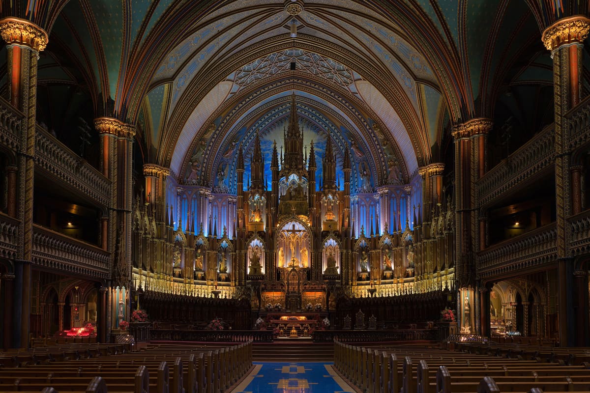 Basilique Notre-Dame de Montréal interior — royal-blue ceiling studded with gold stars, carved walnut reredos, rose-window stained glass. Gothic Revival 1829.